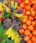 Colorful gummy candy and orange candy balls in Halloween-themed snack assortment.