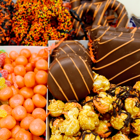 Festive Halloween Boo Box with chocolate-covered pretzels, cookies, colorful popcorn, and candies in spooky colors.