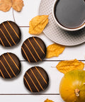 Fall-themed chocolate cookies with coffee, surrounded by autumn leaves and a small pumpkin.