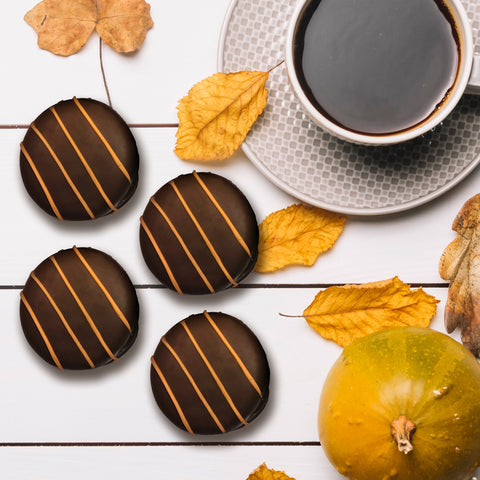 Fall-themed chocolate cookies with coffee, surrounded by autumn leaves and a small pumpkin.