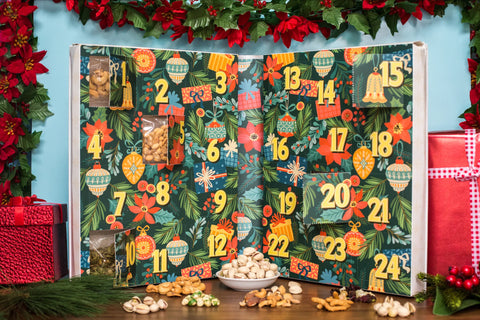 Gourmet nuts and snacks advent calendar with festive design for 24-day holiday countdown, surrounded by holiday decorations.