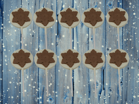 Set of 10 milk and white chocolate snowflake lollipops on a blue wooden background, perfect for festive Christmas gifting.