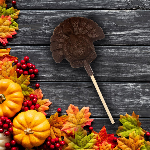 Chocolate turkey lollipop on wooden table with autumn leaves and mini pumpkins, part of the Thanksgiving Nut Tray gift set.